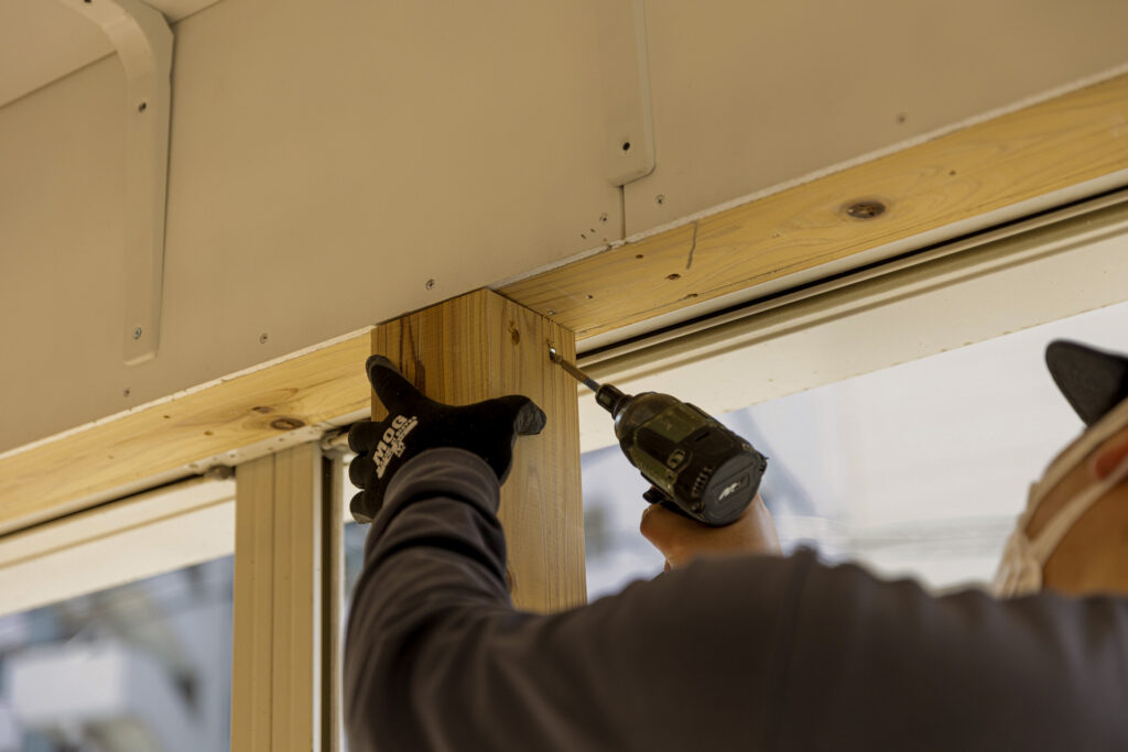 柱を電動ドライバーで固定する作業員