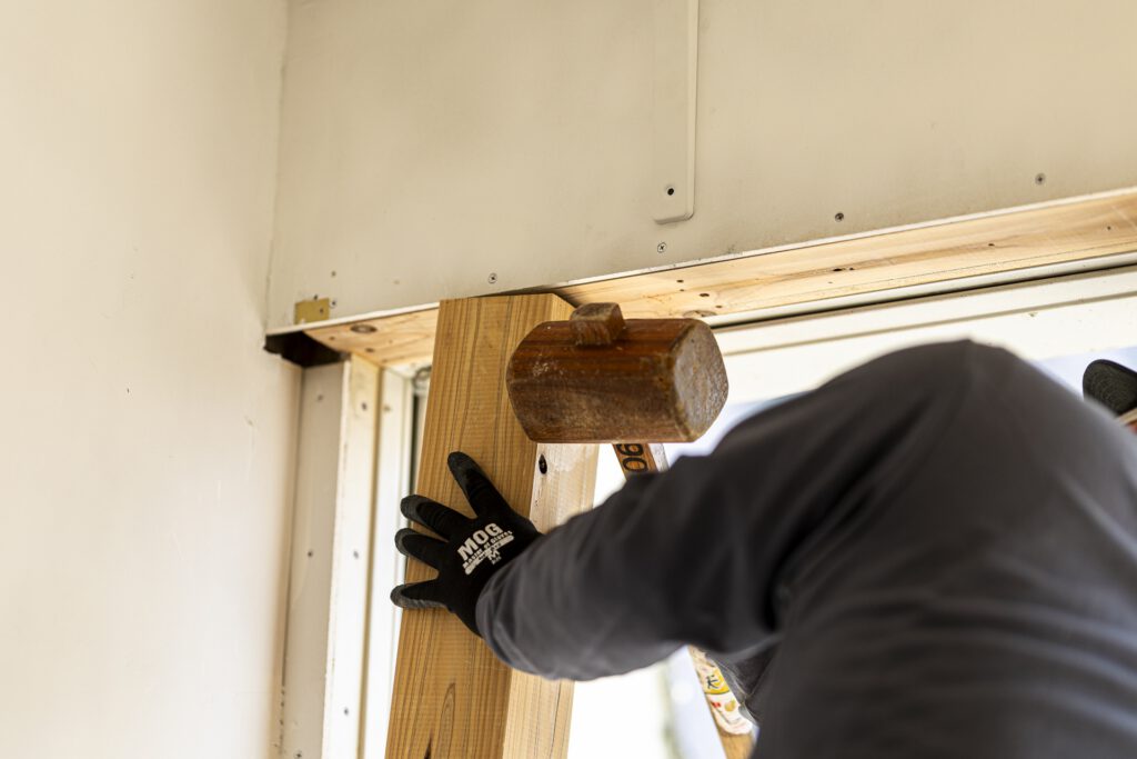 柱を木槌で打ち付ける作業員