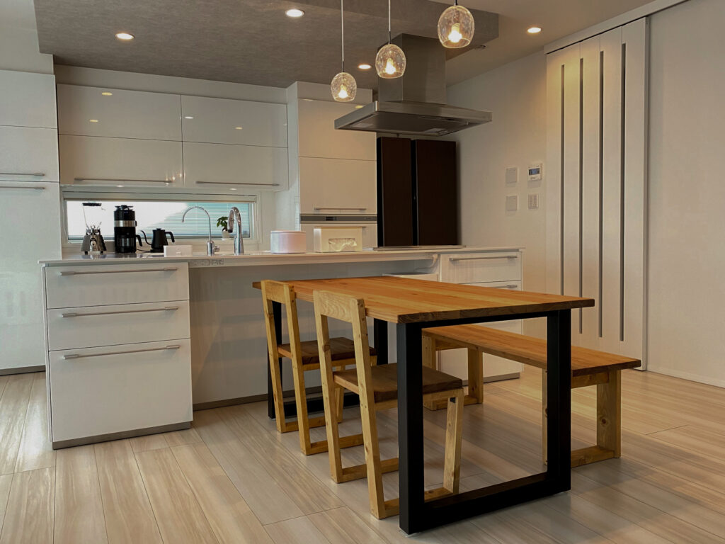 アイアンウッド調のダイニングテーブルと、白いカウンターキッチン